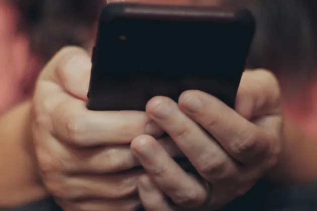 Two hands hold a mobile phone.