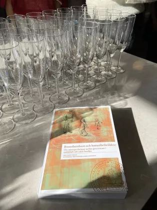 Thesis book on a table with champagne glasses in the background.