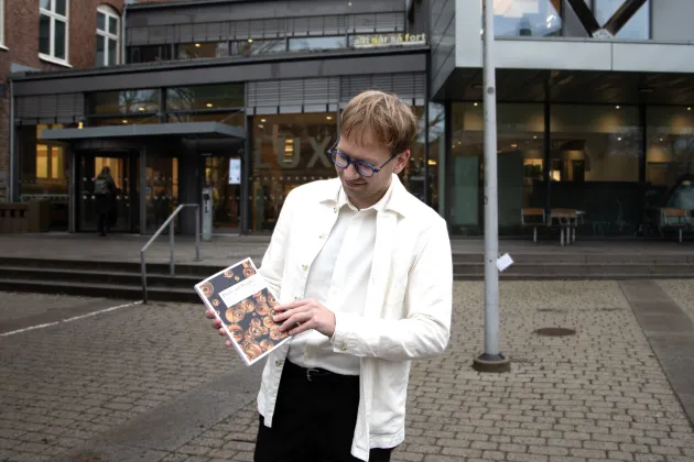 Isak Engdahl håller upp sin avhandling framför Lux.